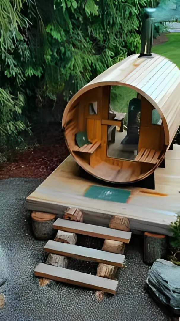 Cozy wooden barrel sauna with a small deck and steps in a natural setting.